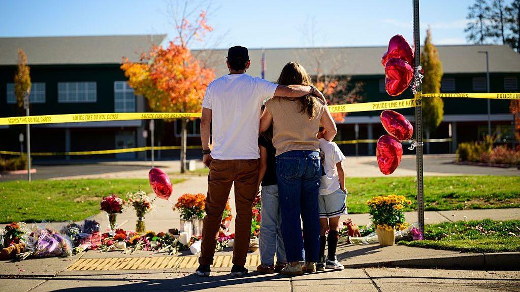 Community members grieve at the site of a makeshift memorial in front of Silver Rail Elementary School