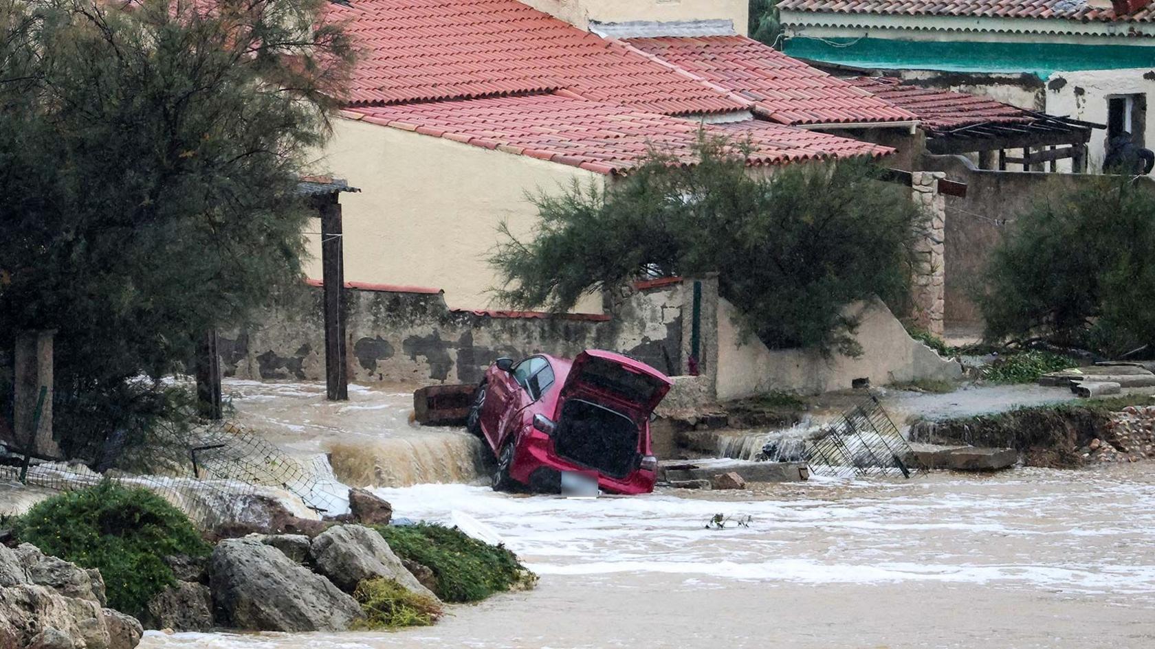 A damaged red car in a flooded area