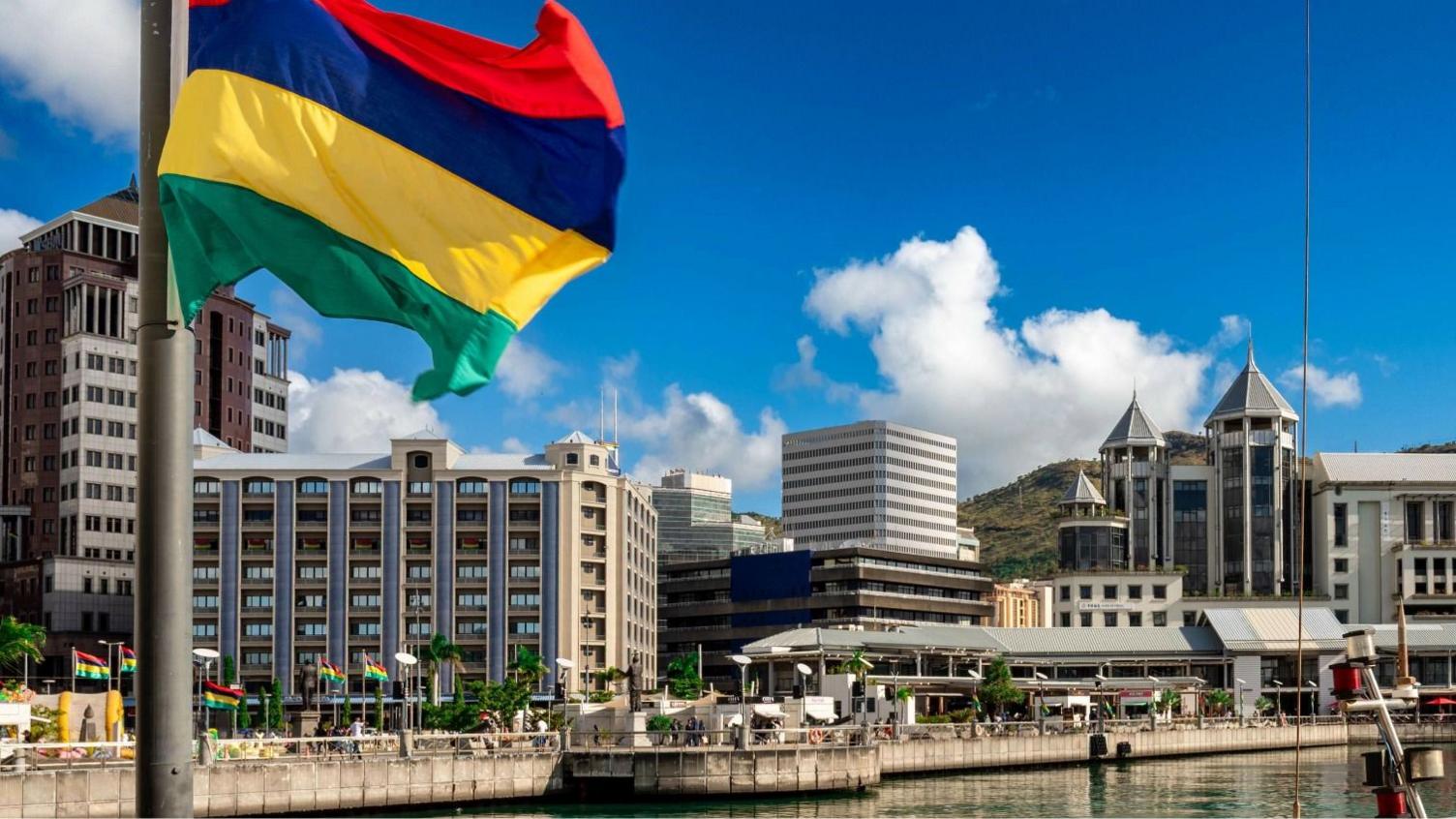View of the promenade at Caudan Waterfront in Port Louis with a waving Mauritian flag in the foreground