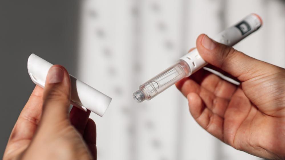 Woman holds weight‑loss injection pen